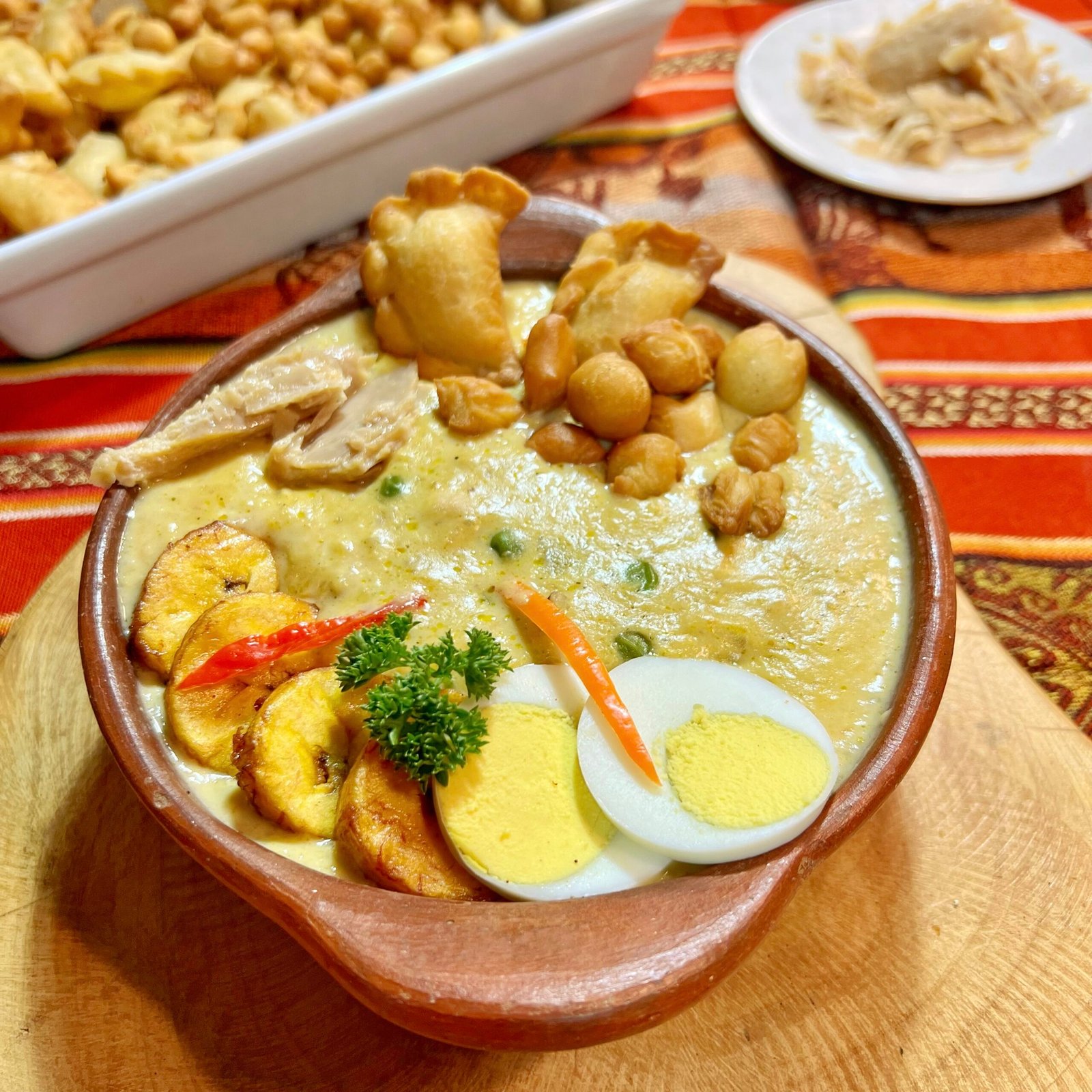 Fanesca ecuatoriana tradicional con acompañantes típicos como huevo, plátano frito y empanadas, plato representativo de Semana Santa.